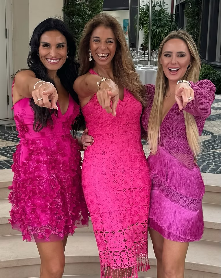 Three society women pointing at camera smiling