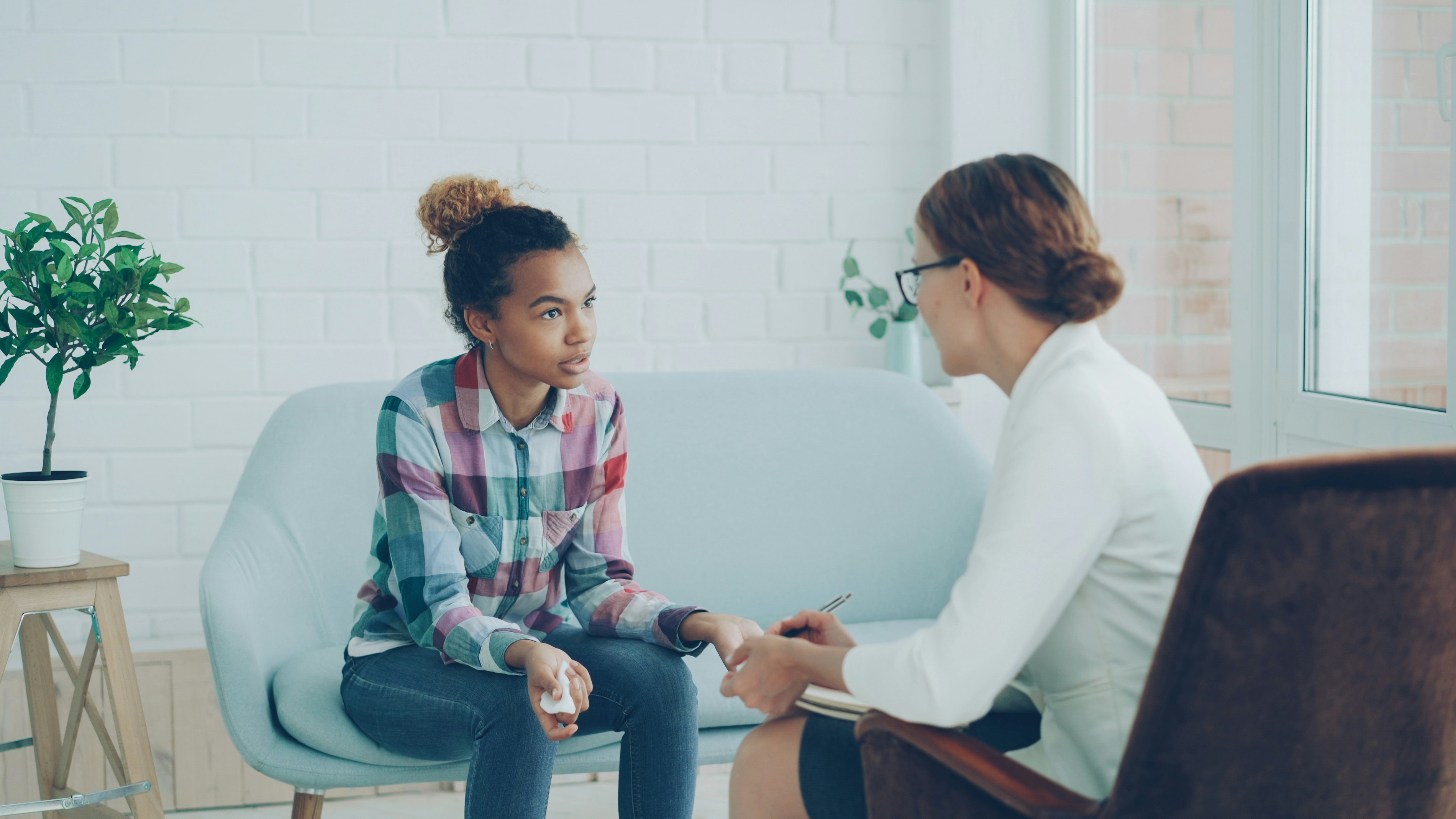 Woman on white couch speaking to counselor 