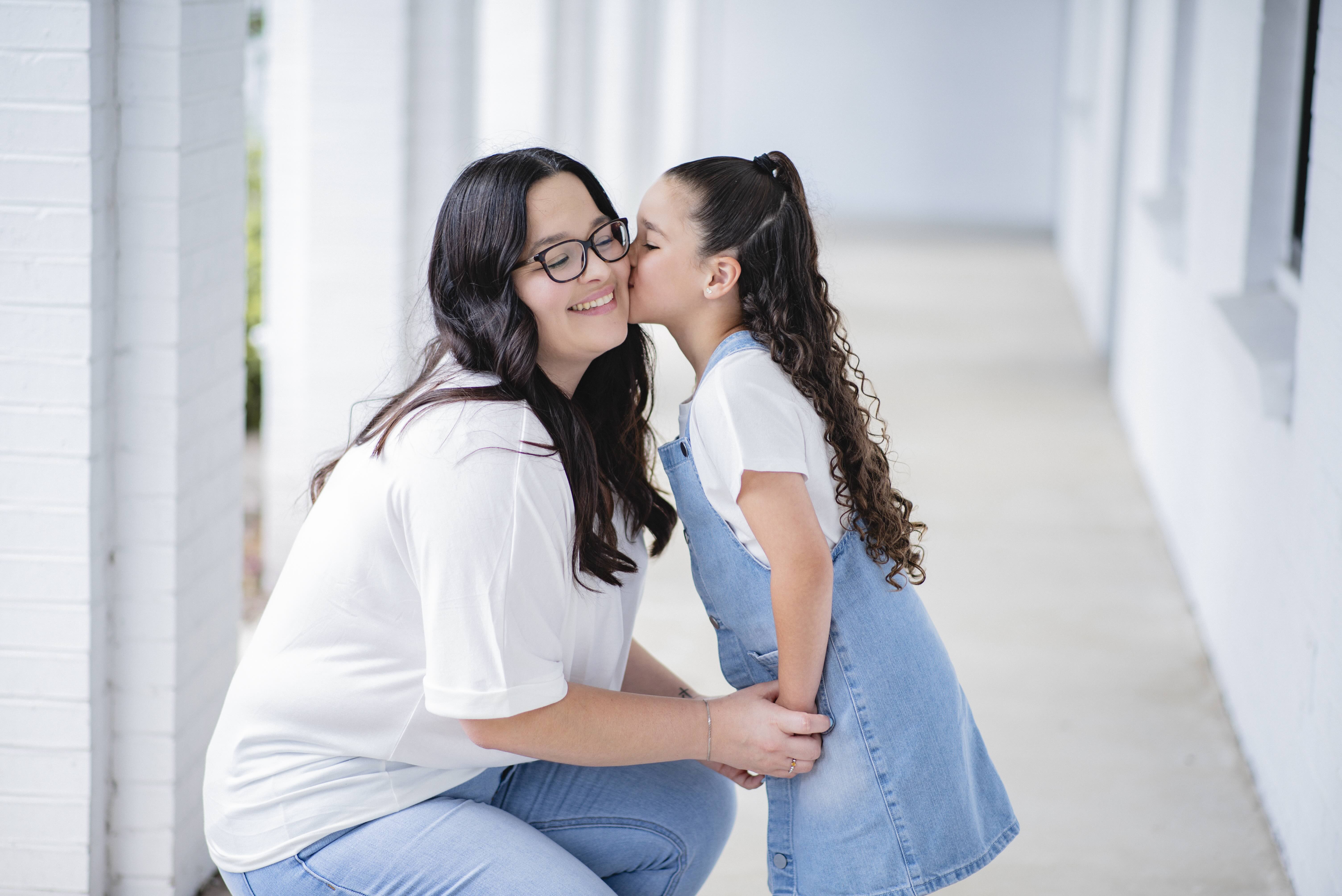 Mother with her two daughters holding a Hearts for Moms logo cutout
